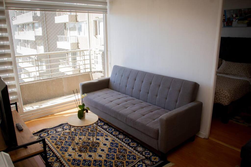 Sofá azul en la sala de estar con ventana en Quedate aqui Centro Concepcion I, en Concepción