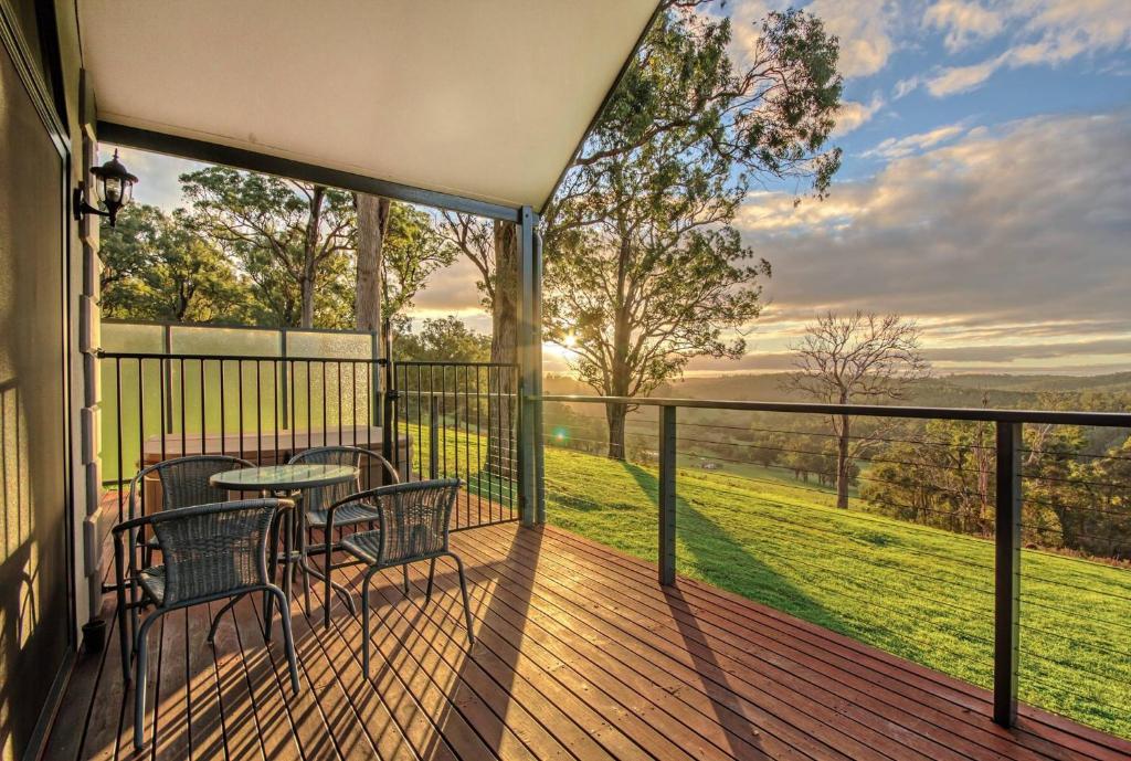 a balcony with tables and chairs and a view of a field at Scarlet Woods in Quinninup