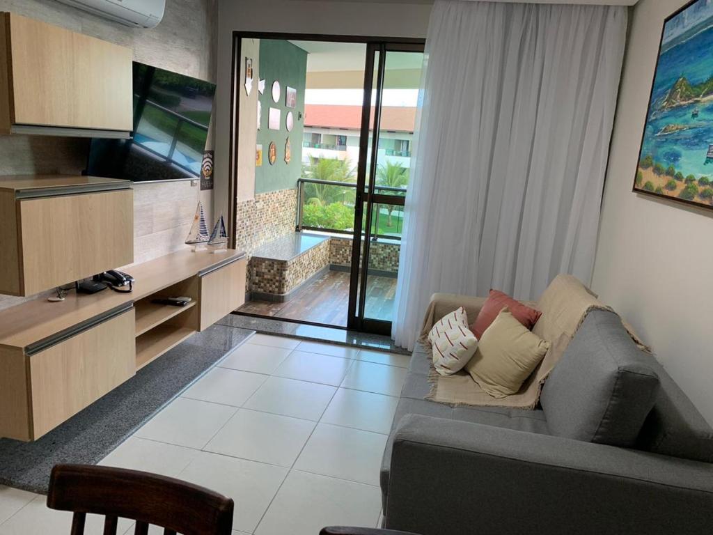 a living room with a couch and a television at Carneiros Beach Resort 315 E in Praia dos Carneiros