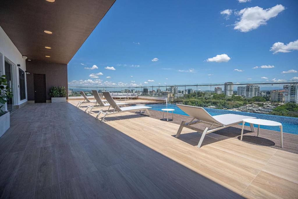 a deck with lounge chairs and a pool on a building at Soha Panorama in Santiago de los Caballeros