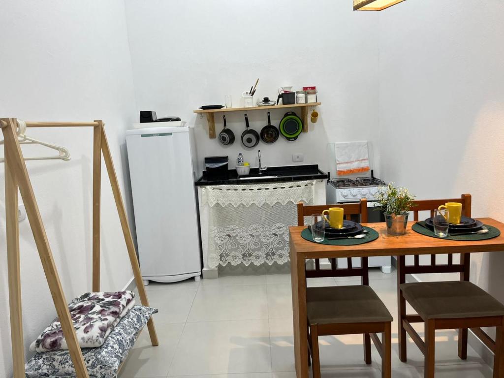 a kitchen with a table and chairs and a refrigerator at Chalés Caminhos do Cacau Camburi in Sao Paulo