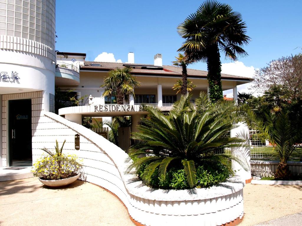 une maison blanche avec des palmiers devant elle dans l'établissement Residenza ZACCOLO, à Lignano Sabbiadoro