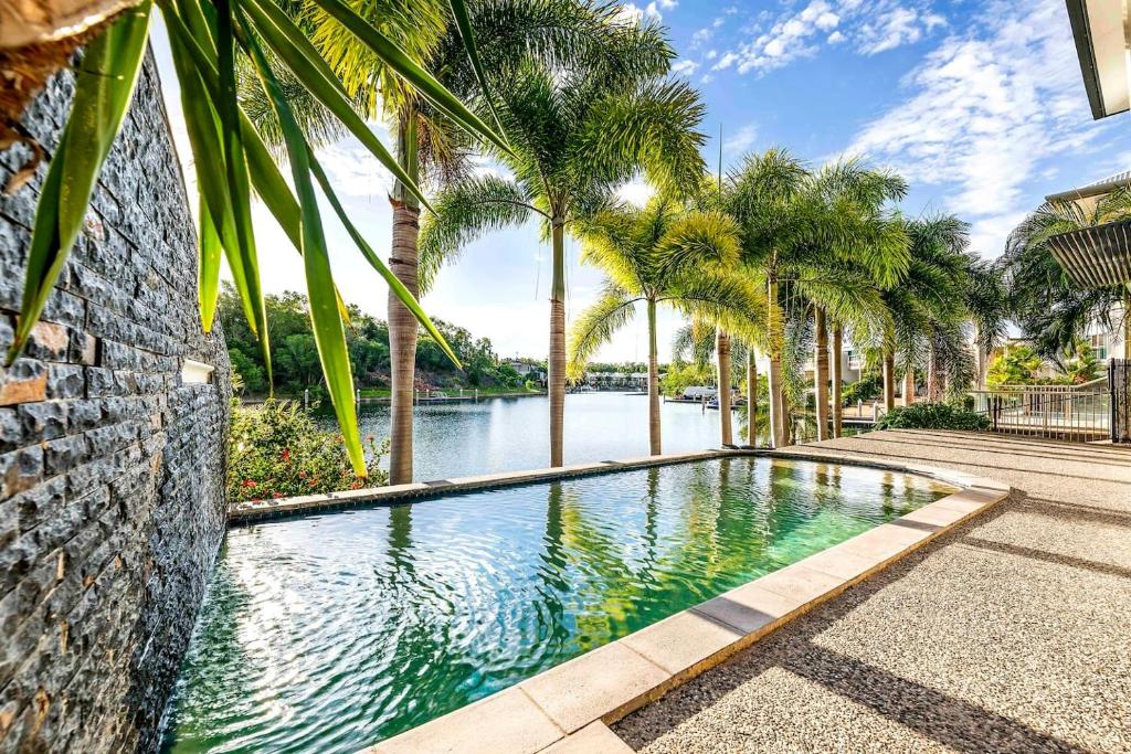 a swimming pool with palm trees and a river at Luxe Bayview Oasis with Dream Waterfront Pool in Stuart Park