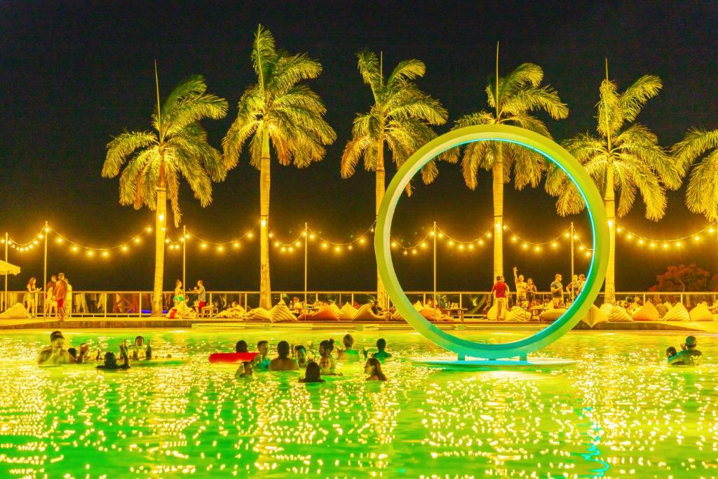 Leute in einem Schwimmbad nachts mit einem Ring im Wasser in der Unterkunft Coral Ocean Resort in Saipan