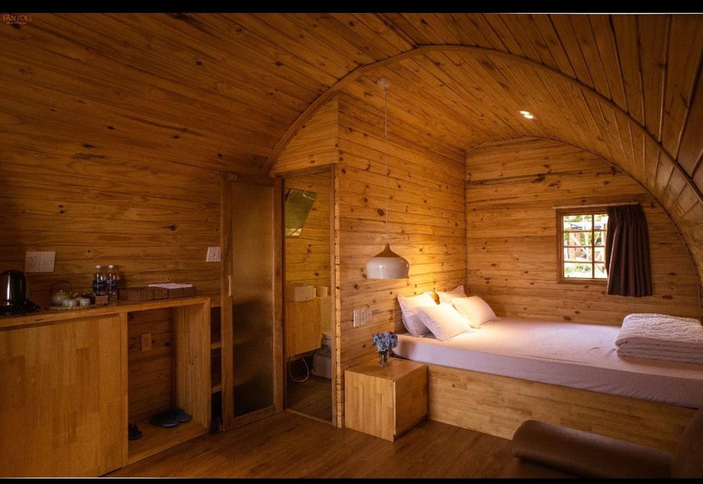 a bedroom with a bed in a wooden cabin at Tanyoli Resort in Phan Rang