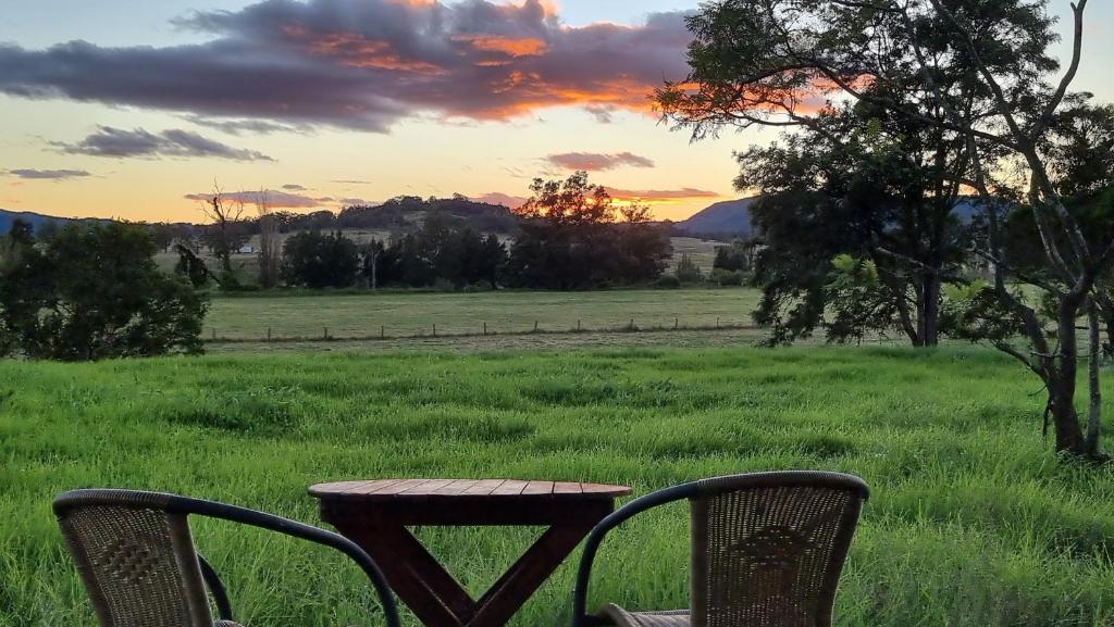 een tafel en stoelen in een veld met zonsondergang bij Vacy Hunter Valley Lodge in Vacy