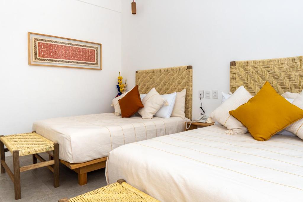 una habitación de hotel con 2 camas y una silla en Santa Cecilia Hotel, en Oaxaca City