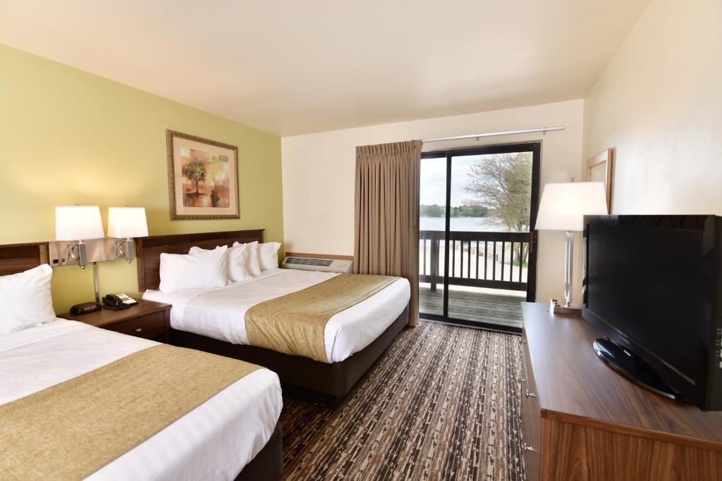 a hotel room with two beds and a flat screen tv at Bakers Sunset Bay Resort in Wisconsin Dells