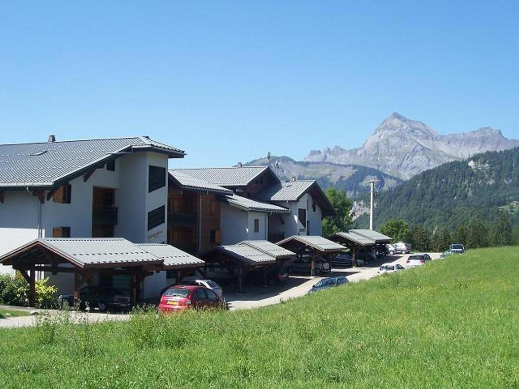budynek z samochodami zaparkowanymi przed nim z górą w obiekcie Appartement rénové avec terrasse, proche ski-bus et commerces, Notre-Dame-de-Bellecombe - FR-1-505-178 w mieście Notre-Dame-de-Bellecombe