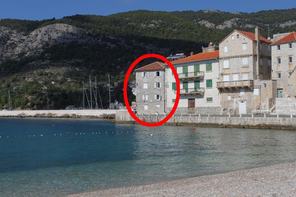 um círculo vermelho sentado em cima de uma massa de água em Apartments and rooms by the sea Komiza, Vis - 2431 em Komiža