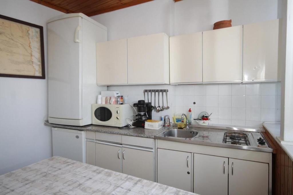 a kitchen with white cabinets and a sink and a microwave at Apartments and rooms by the sea Komiza, Vis - 2431 in Komiža