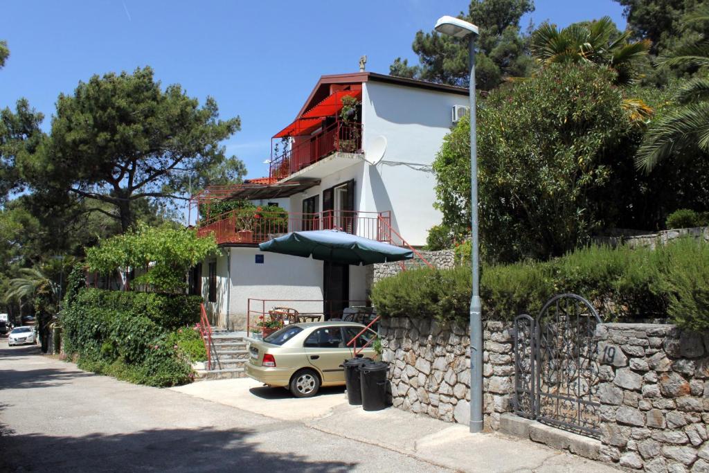 a car parked in front of a white house at Apartments by the sea Mali Losinj (Losinj) - 2493 in Mali Lošinj