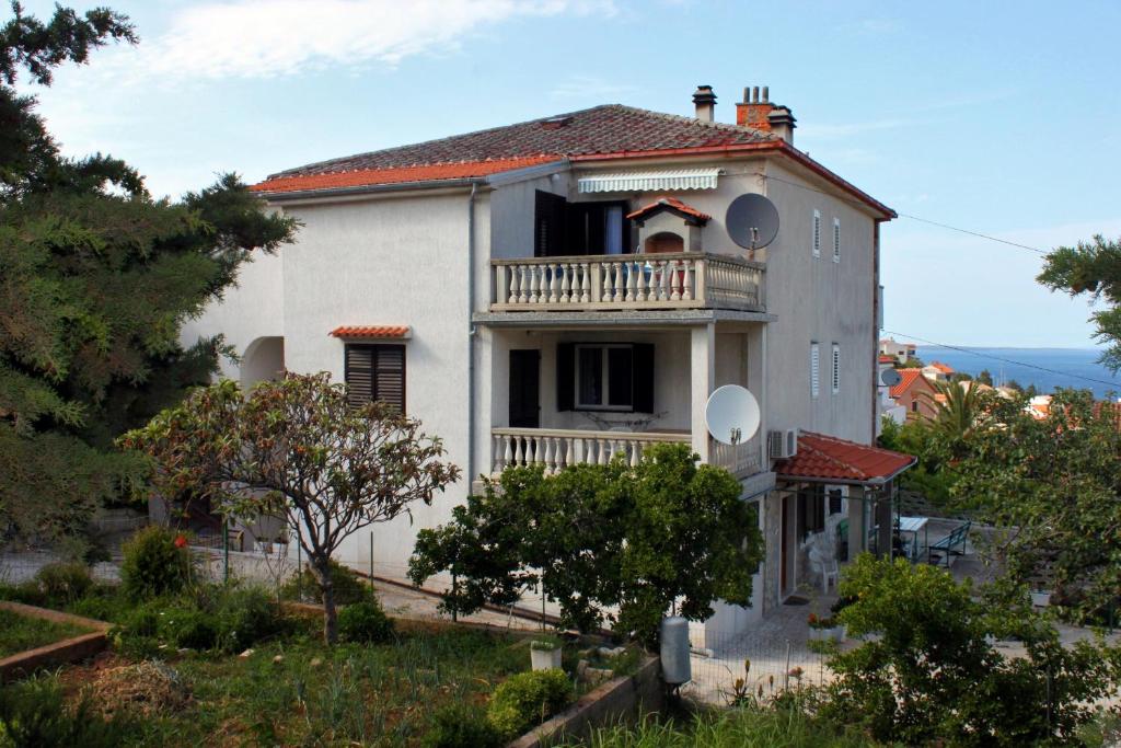 a white house with a balcony on a hill at Apartments with a parking space Mali Losinj (Losinj) - 2507 in Mali Lošinj