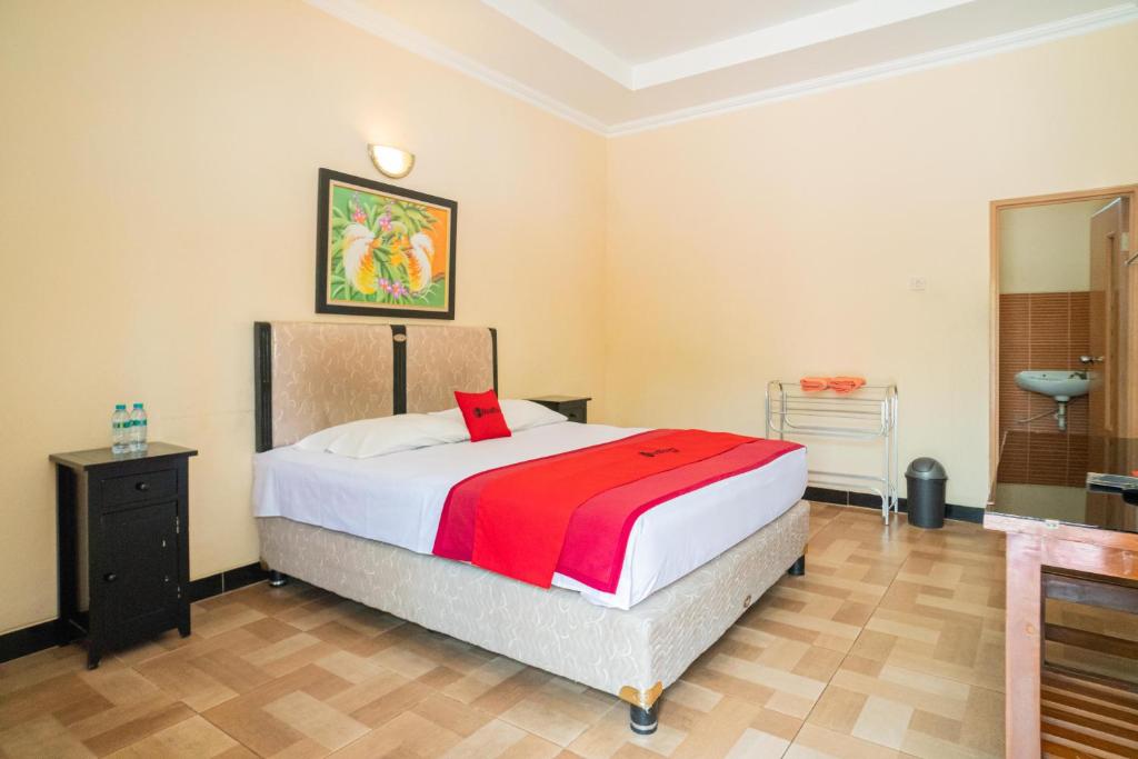 1 dormitorio con 1 cama grande con manta roja en RedDoorz @ Panglima Sudirman Madiun en Madiun