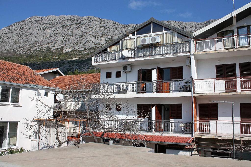 a white apartment building with a mountain in the background at Twin Room Podaca 2613d in Podaca