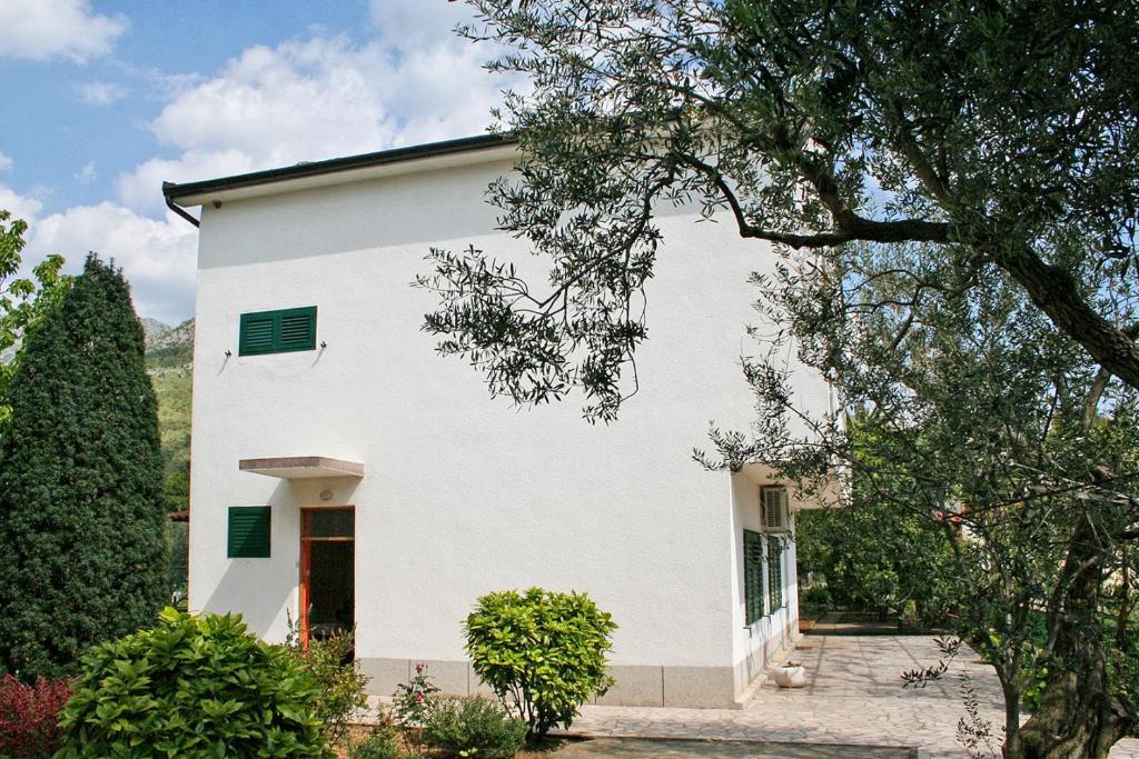 a white house with green shutters on it at Apartments and rooms by the sea Zaostrog, Makarska - 2661 in Zaostrog