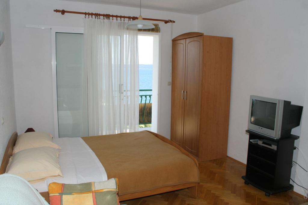 a bedroom with a bed and a tv and a window at Apartments by the sea Igrane, Makarska - 2679 in Igrane