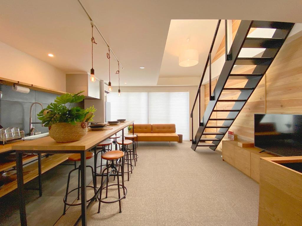 a kitchen with a bar with stools and a staircase at Joka Base in Kakegawa