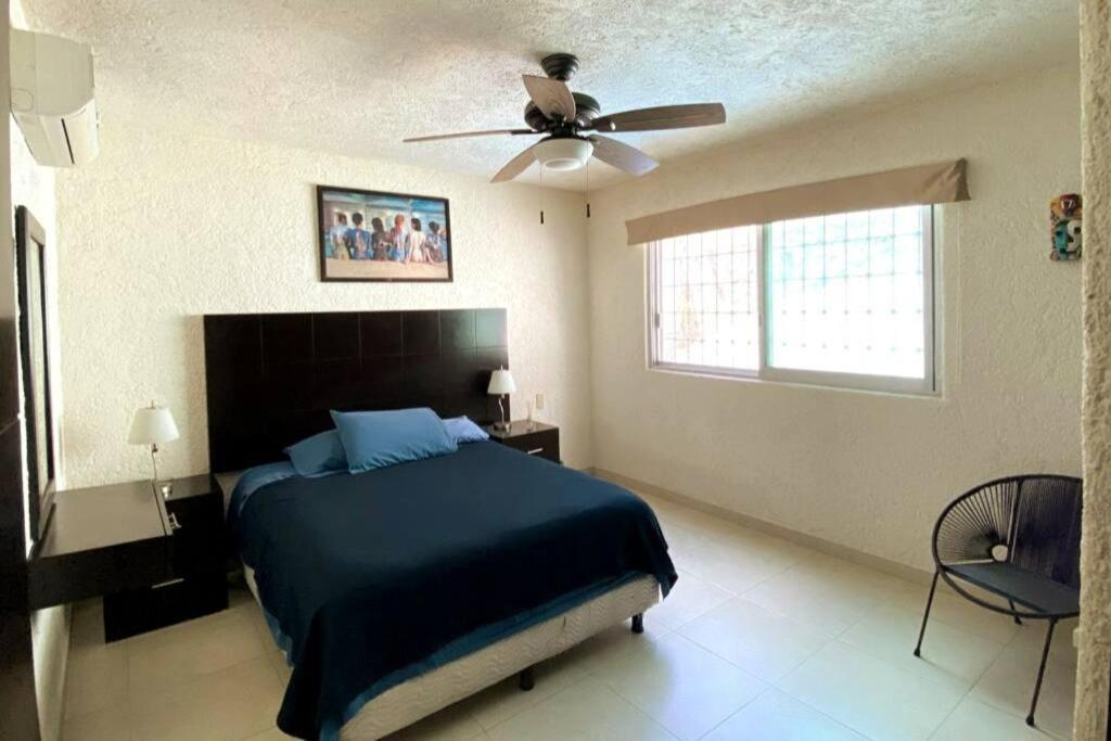 um quarto com uma cama e uma ventoinha de tecto em Hermoso departamento con alberca em Acapulco