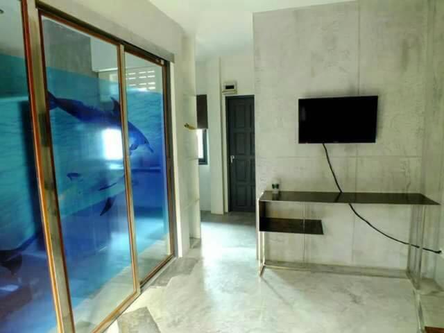 un soggiorno con TV e parete in vetro di BEACHWAY APARTMENT a Ban Lamai