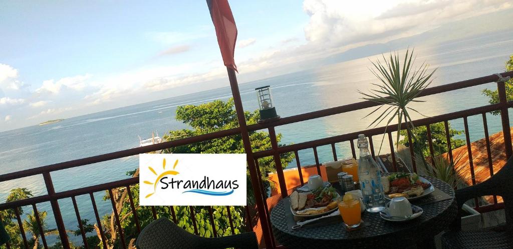 a table on a balcony with a view of the ocean at Strandhaus Condotel in Moalboal