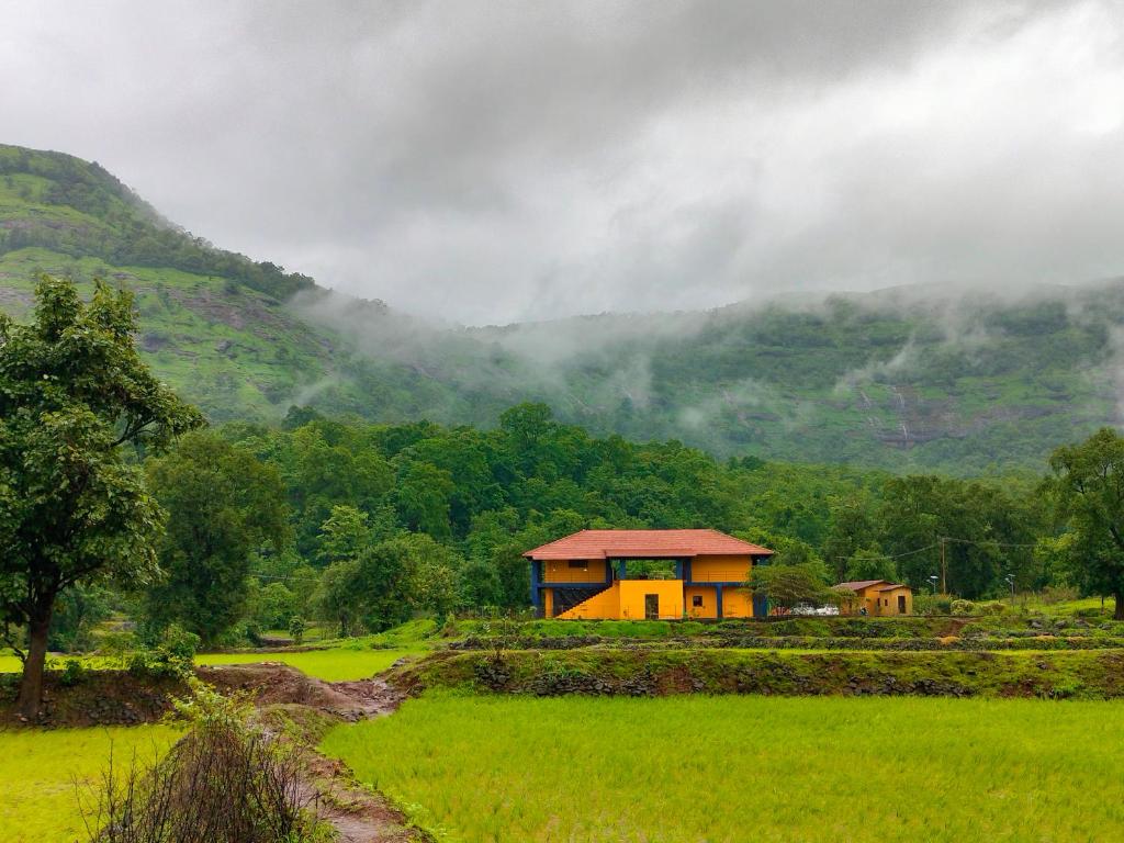 a house in a field with mountains in the background at King's Landing for Pets in Karjat