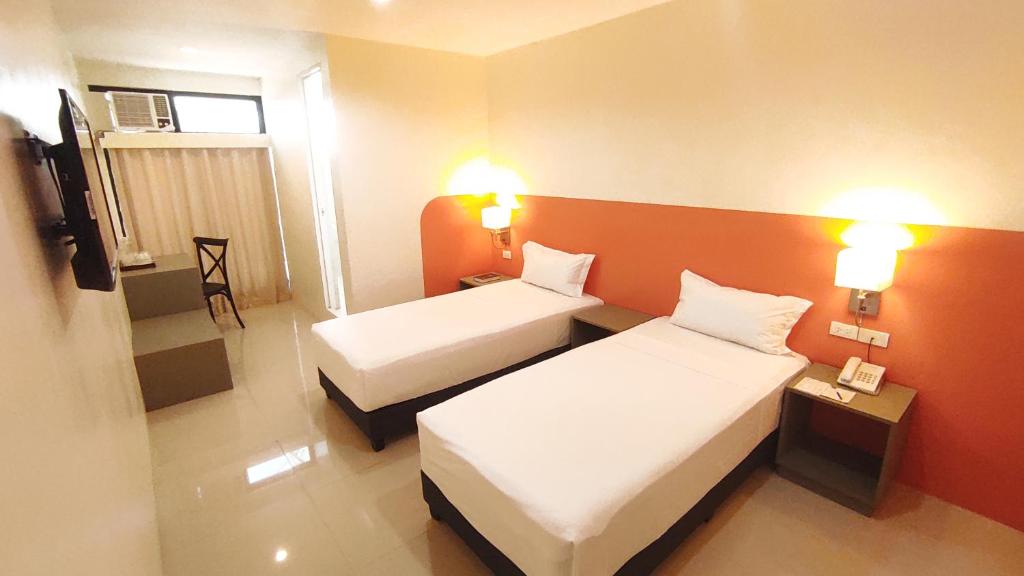 a hotel room with two beds and a television at Travelbee Airport Inn in Mactan