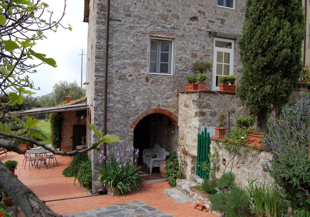 a stone house with a courtyard with flowers and plants at Borgo Bucatra Buonvento in Chiatri