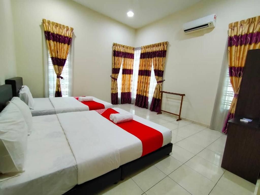 a bedroom with two beds with red and white at D' Anjung Inn in Tangkak