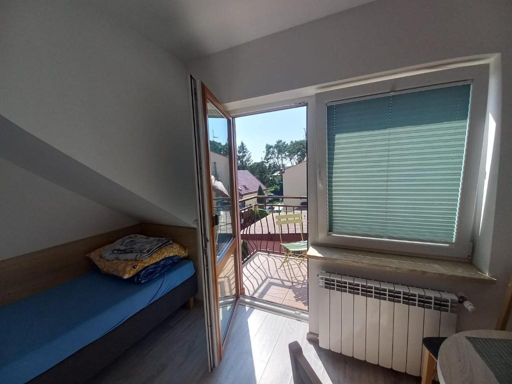 a small room with a window with a bed and a balcony at Pokoje Goscinne TOMASZ in Międzywodzie
