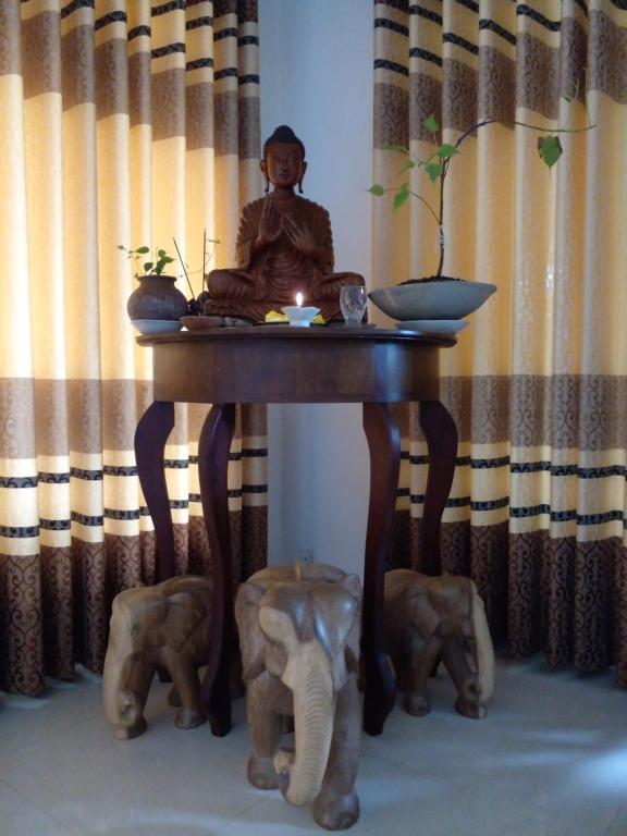 a statue of a monk sitting on a table with elephants at Muthu Villa Sri Lanka in Kalutara