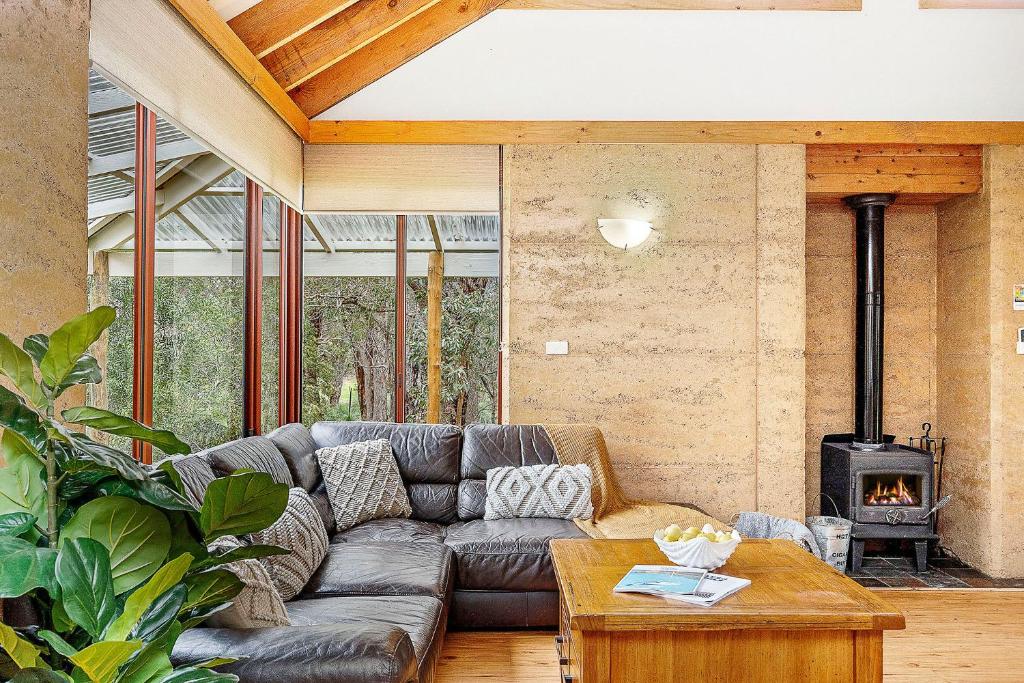 ein Wohnzimmer mit einem Sofa und einem Kamin in der Unterkunft Possum Cottage - Woodstone Estate in Dunsborough