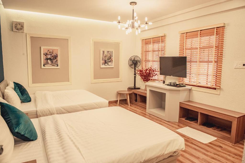 a white room with two beds and a television at Villa Hoa Da in Da Lat