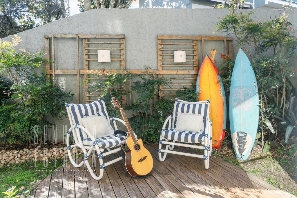 dwa krzesła i gitara obok dwóch desek surfingowych w obiekcie Embaúba House Casa de Praia, Praia Particular. w mieście Florianópolis