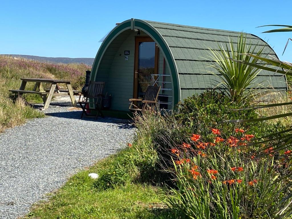 uma tenda de cúpula verde com uma mesa de piquenique e flores em Earls View Pod em Carna