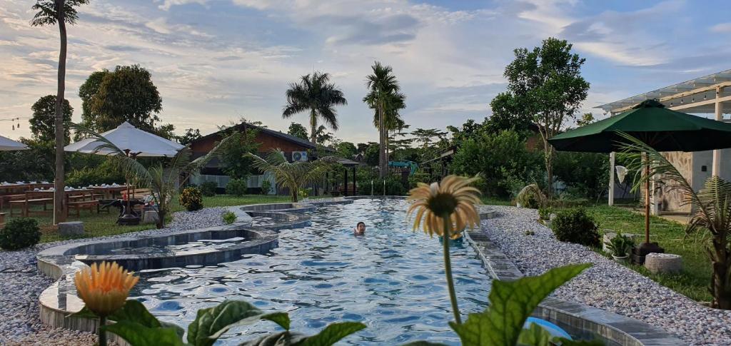 a swimming pool in a resort with a flower in the foreground at MOMIZI INN in Ba Vì