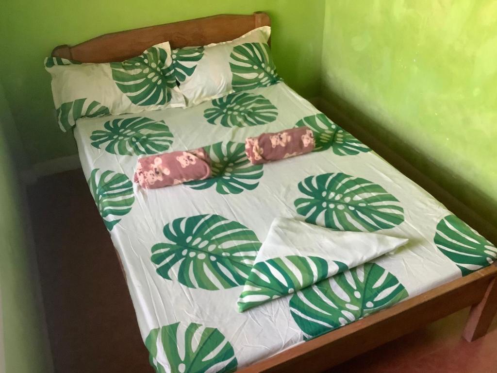 Cama pequeña con sábanas y almohadas verdes y blancas en HFA Bldg en Sipalay