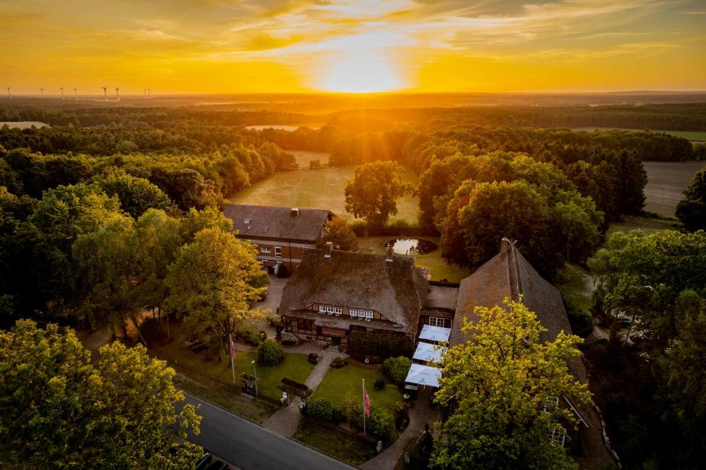 una vista aérea de una casa con la puesta de sol en el fondo en Hotel Landhaus Höpen, en Schneverdingen