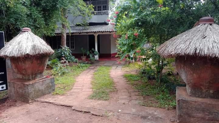 a house with two huts on the side of it at Sigiriya Farm House in Sigiriya