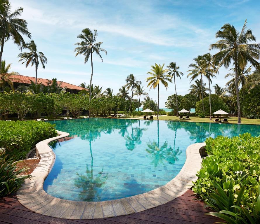 a pool at a resort with palm trees in the background at Cinnamon Bentota Beach - Signature Selection in Bentota
