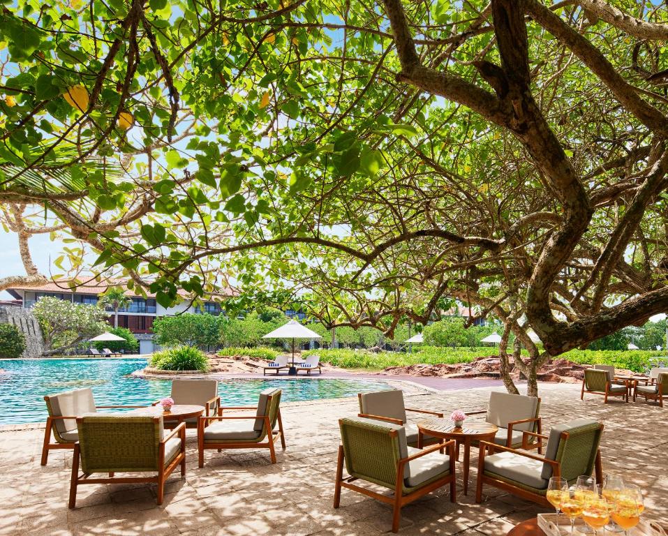 a group of tables and chairs next to a pool at Cinnamon Bentota Beach - Signature Selection in Bentota