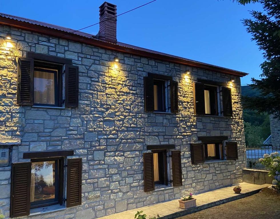 a stone house with windows and lights on it at Cosy lake house, μια ανάσα πριν τη λίμνη in Kalyvia