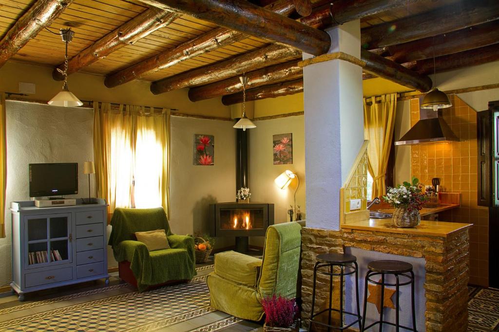 a living room with a fireplace and green chairs at Finca la Colorá in Fuenteheridos