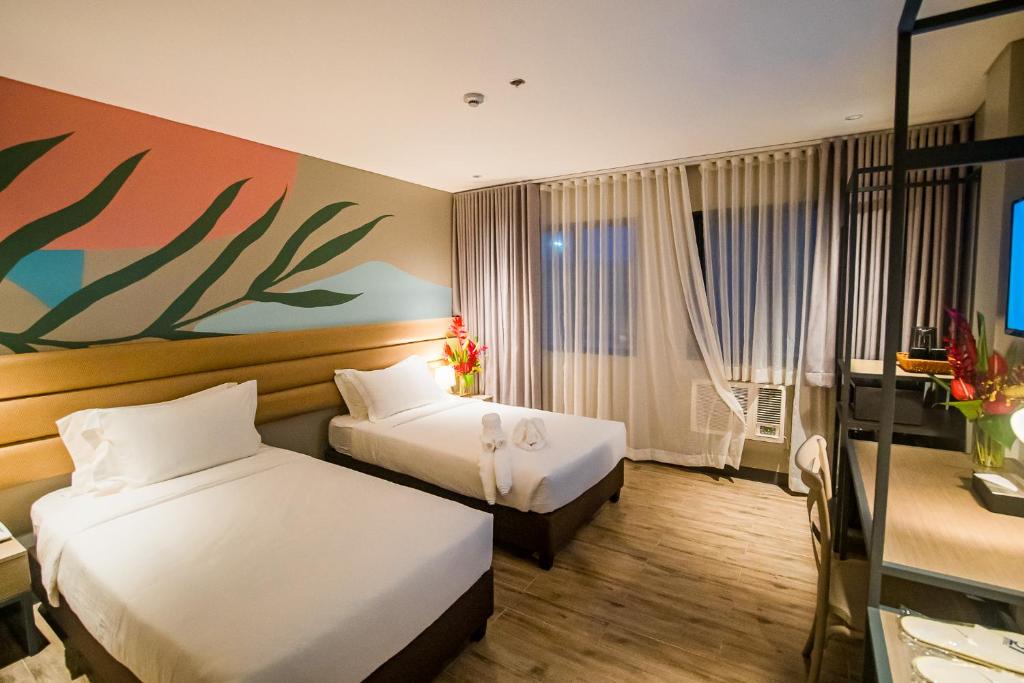 a hotel room with two beds and a painting on the wall at 1521 Hotel & Spa in Mactan