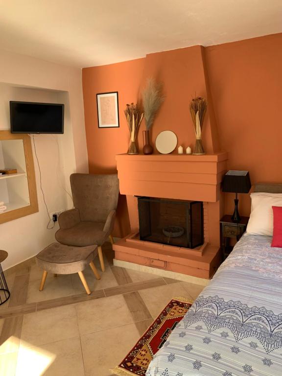 ein Schlafzimmer mit einem Kamin, einem Bett und einem Stuhl in der Unterkunft Zacharos Elegant Studio in Leonidi