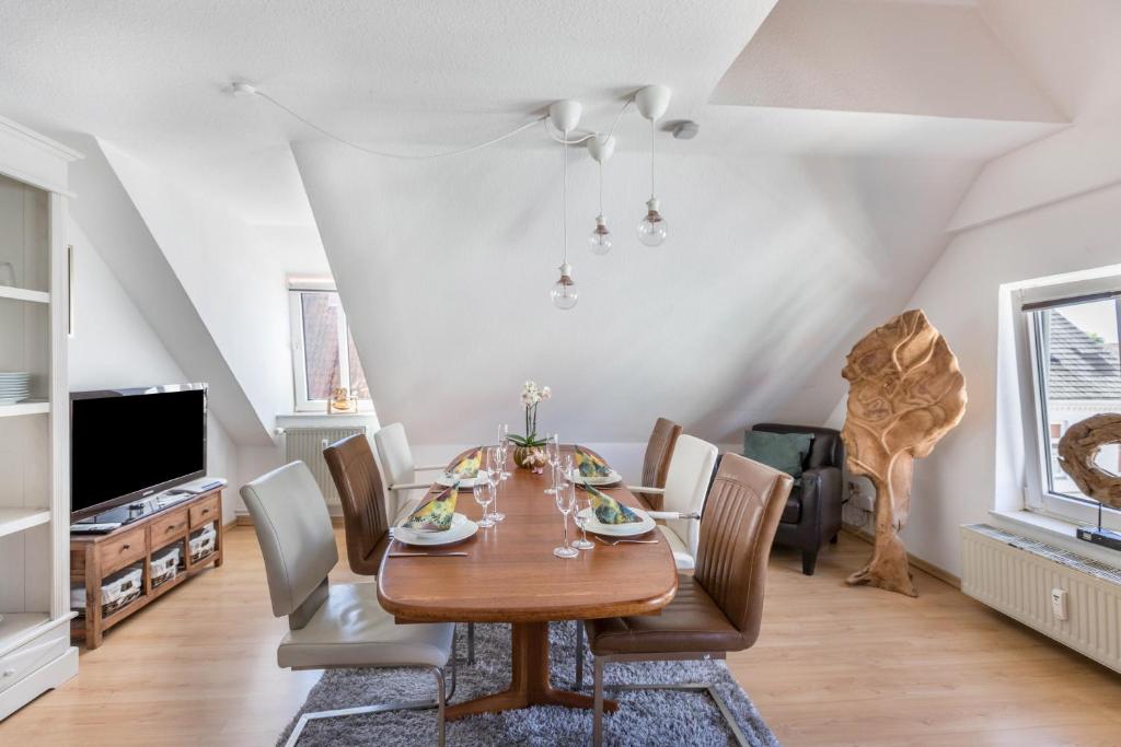 a dining room with a wooden table and chairs at Blumenhaus-apartment Friedrichstadt in Friedrichstadt