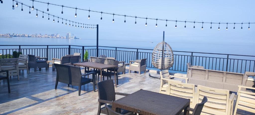 Guest house Garden Beach في باتومي: مطعم بطاولات وكراسي على شرفة مطلة على المحيط