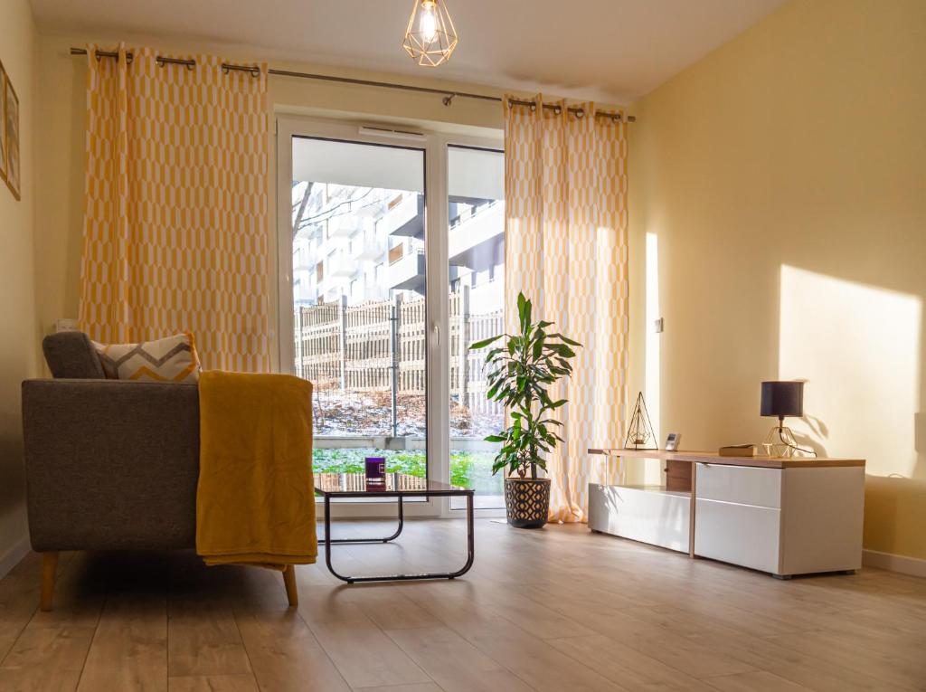 un soggiorno con divano e una grande finestra di Przytulny apartament z ogródkiem a Cracovia