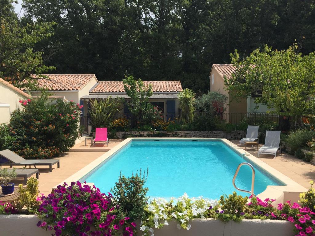 a swimming pool in a yard with flowers at Les Hauts d'Eyragues gite Rêverie Meublé classé 4 étoiles in Eyragues