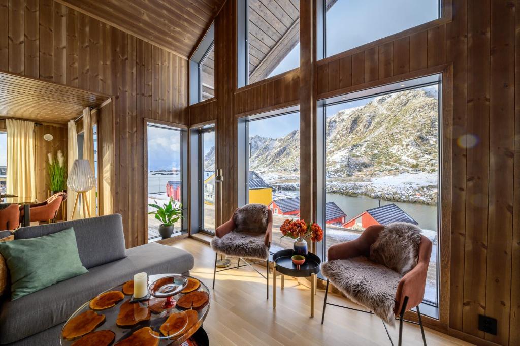 a living room with a couch and chairs and windows at Superior Cabin Ballstad Lofoten in Ballstad